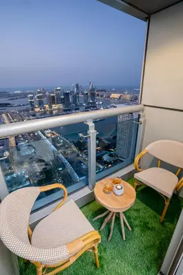 a balcony with two chairs and a table with a view of a city at VIBES by Beds and Company - 51st Floor, Full Sea View in Dubai