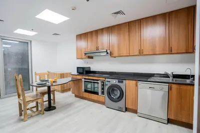a kitchen with wooden cabinets and a washing machine at VIBES by Beds and Company - 51st Floor, Full Sea View in Dubai