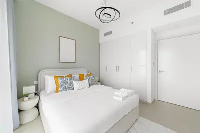 a white bedroom with a white bed with orange pillows at Silkhaus Ultra Luxury 1BDR in New Tower of Downtown in Dubai