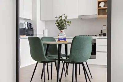 a kitchen with a table and four green chairs at Silkhaus Ultra Luxury 1BDR in New Tower of Downtown in Dubai