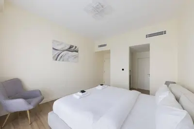 a white bedroom with a bed and a chair at Luxury Living on the Top Floor Full Marina View in Dubai