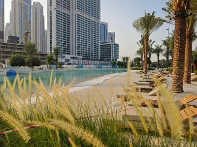 a beach with benches and palm trees in a city at Dubai Creek Escape: Luxury 3BR Nautical Grandeur in Dubai
