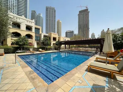 a large swimming pool with two chairs and an umbrella at FIRST CLASS 1BR Tranquil Oasis in Old Town in Dubai