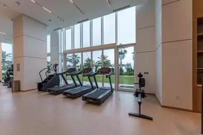 a gym with treadmills and ellipticals in a room with windows at Maison Privee - Seaside JBR Living w/ Open Sea & Bluewaters Views in Dubai