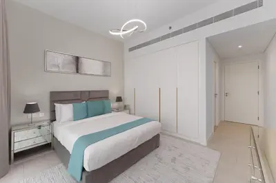 a bedroom with a large bed with blue pillows at Maison Privee - Seaside JBR Living w/ Open Sea & Bluewaters Views in Dubai
