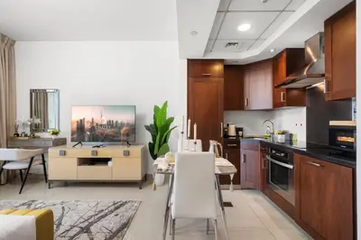 a kitchen with wooden cabinets and a dining room at Luxury Studio, 29 Boulevard near Burj Khalifa Downtown - Chalet Homes in Dubai