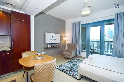 a hotel room with a bed and a table and a room at Luxury Escapes - Modern Studio Apt with Balcony near Dubai Mall - 29 Blvd in Dubai