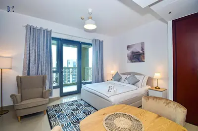 a bedroom with a bed and a chair and a table at Luxury Escapes - Modern Studio Apt with Balcony near Dubai Mall - 29 Blvd in Dubai