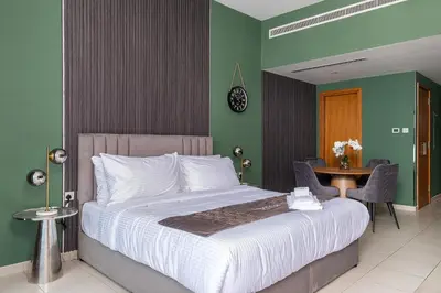 a bedroom with a large bed and a table with chairs at Escape24 Spacious Studio with Balcony near Dubai Mall in Dubai