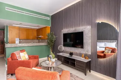 a living room with orange furniture and a tv at Escape24 Spacious Studio with Balcony near Dubai Mall in Dubai