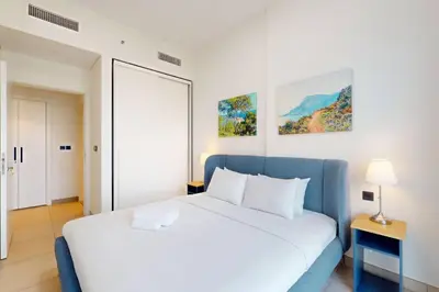 a bedroom with a white bed and a blue couch at Socio Tower 2 - Neat Two Bedroom in Dubai