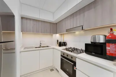 a kitchen with white cabinets and a stove top oven at Your Exclusive Retreat in Dubai Hills by Suiteable in Dubai