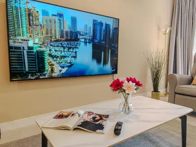 a living room with a tv hanging on a wall at Modern, spacious, Luxe 5BR plus Maid condo in JBR, near JBR Beach, Marina view, By La Buena Vida Holiday Homes in Dubai