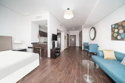 a living room with a bed and a blue couch at StoneTree - Spacious Studio - The Matrix in Dubai