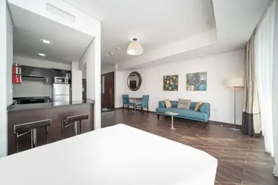 a living room with a blue couch and a kitchen at StoneTree - Spacious Studio - The Matrix in Dubai