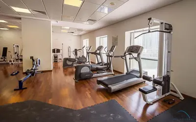 a gym with several tread machines in a room at Comfortable 1BR Apartment in Marina Tower, Dubai Marina by Deluxe Holiday Homes in Dubai