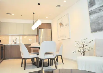 a dining room with a table and white chairs at Sea Breeze Oasis in Dubai