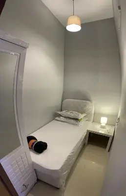 a small white room with a bed and a lamp at MOE Hostel By PHM in Dubai