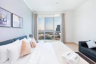 a bedroom with a large white bed and a couch at Incredible Fountain Views 2.5 BR Burj Residences in Dubai