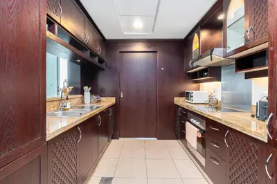 a large kitchen with wooden cabinets and a sink at Incredible Fountain Views 2.5 BR Burj Residences in Dubai