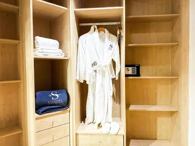 a walk in closet with a white robe and shoes at Bright 2BR Apartment with Garden View - Palm Jumeirah in Dubai