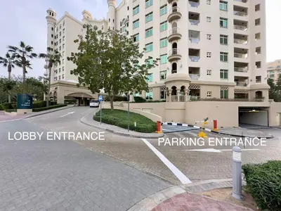 a street in front of a building with a parking entrance at Bright 2BR Apartment with Garden View - Palm Jumeirah in Dubai