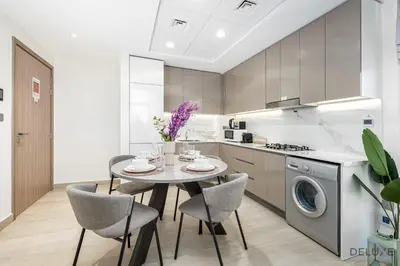 a kitchen with a table and chairs and a washing machine at Comfy 1BR in Azizi Riviera 8, Al Merkadh by Deluxe Holiday Homes in Dubai