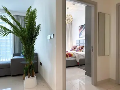 a living room with a couch and a palm tree at Vibrant 1BR Apartment with Marina & Ocean View in Dubai