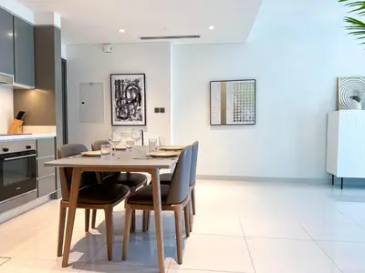 a kitchen and dining room with a wooden table and chairs at Vibrant 1BR Apartment with Marina & Ocean View in Dubai