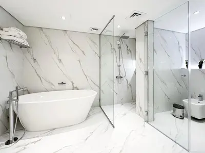 a white bathroom with a tub and a glass shower at Charming Ocean View 1BR Apartment at 5 Star Resort in Dubai