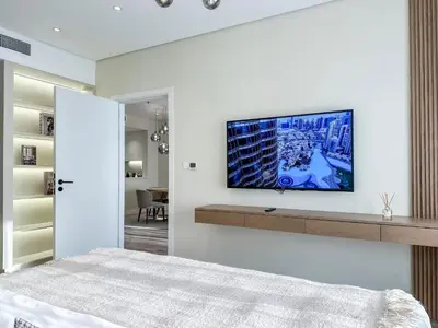 a bedroom with a tv on a white wall at Charming Ocean View 1BR Apartment at 5 Star Resort in Dubai