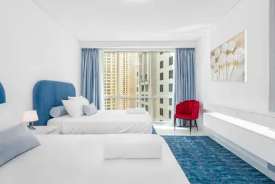 a hotel room with two beds and a red chair at High class apartment in Dubai