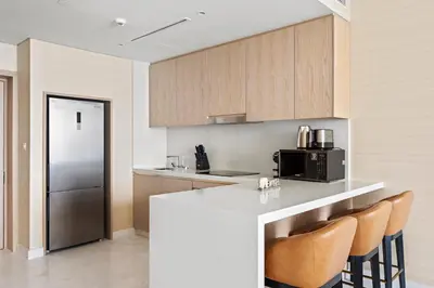 a kitchen with a counter with chairs and a refrigerator at Stonetree - Full Sea View - Luxury Tower with 5 Star Facilities in Dubai