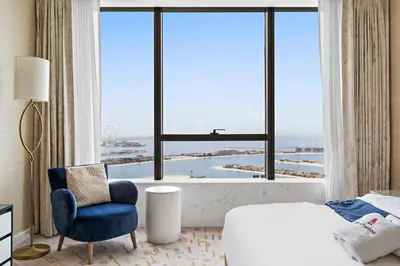 a bedroom with a blue chair and a large window at Stonetree - Full Sea View - Luxury Tower with 5 Star Facilities in Dubai