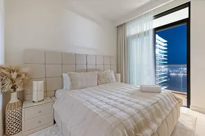 a white bedroom with a bed and a large window at Goldbest - 2bdr Marina view in Dubai