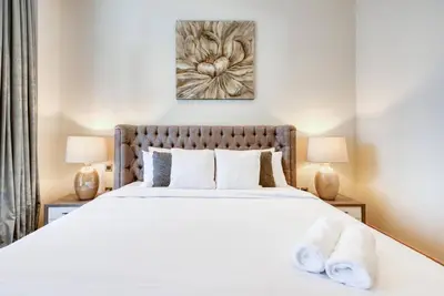 a bedroom with a large white bed with two lamps at RH- Elevated Living, Modern 1BR Oasis at RP Heights walk away to Dubai Mall in Dubai
