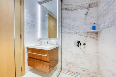 a bathroom with a shower with a sink and a mirror at RH - Burj Khalifa View, 01 BR Bliss at RP Heights, walk away to Dubai Mall in Dubai