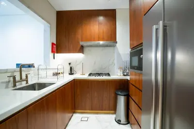 a kitchen with wooden cabinets and a stainless steel refrigerator at RH - Burj Khalifa View, 01 BR Bliss at RP Heights, walk away to Dubai Mall in Dubai