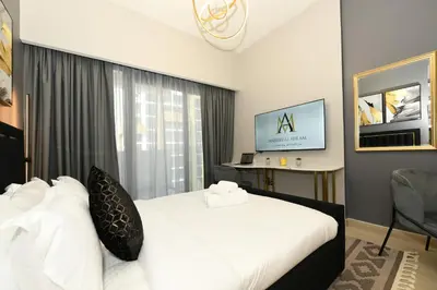 a hotel room with a white bed and a desk at Stylish and Modern Studio at Azizi Riviera - Dubai in Dubai