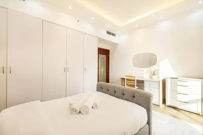 a white bedroom with a bed with two towels on it at Luxury 4-Bedroom with Maids Room, Marina and Ain Dubai Views in Dubai