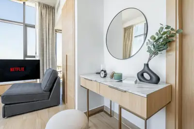 a bathroom with a vanity with a mirror and a chair at Holiday Studio in JVC 2408, Dubai in Dubai