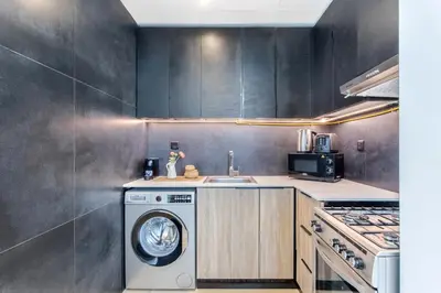 a kitchen with a washing machine and a sink at Holiday Studio in JVC 2408, Dubai in Dubai