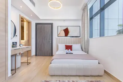 a bedroom with a bed and a desk and a window at Holiday Studio in JVC 2408, Dubai in Dubai