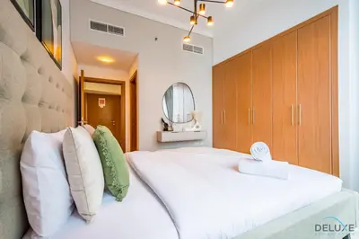 a bedroom with a large white bed and a mirror at Luxury 3BR in Ocean Heights, Dubai Marina by Deluxe Holiday Homes in Dubai