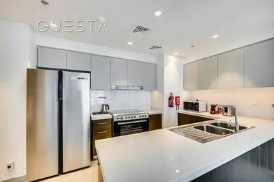 a kitchen with white cabinets and a stainless steel refrigerator at Forte Tower - Dubai Fountain View, Downtown Dubai in Dubai