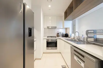 a kitchen with white cabinets and a stainless steel refrigerator at Burj Khalifa View & Dubai Mall Connection in Dubai