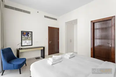 a bedroom with a large bed and a blue chair at WelHome - Charming Breathtaking 1BR Apt. In Damac Hills in Dubai