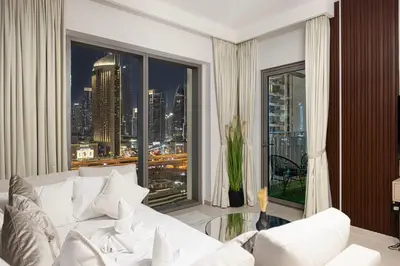 a living room with a white couch and a large window at FULL Burj Khalifa view 2BR with Dubai Mall connection in Downtown in Dubai