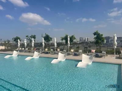 a swimming pool with white chairs and a fountain at Enchanting 1BR Apartment in Socio Tower, Dubai Hills Estate by Deluxe Holiday Homes in Dubai