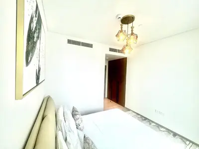 a white bedroom with a bed and a chandelier at High Floor, 1 Bedroom in Palace Residence in Dubai